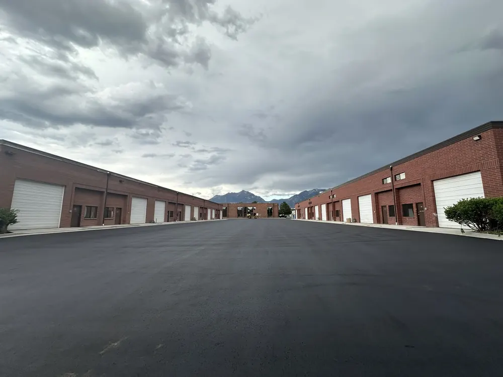 Two rows of brick industrial units with roll up doors and mountains behind