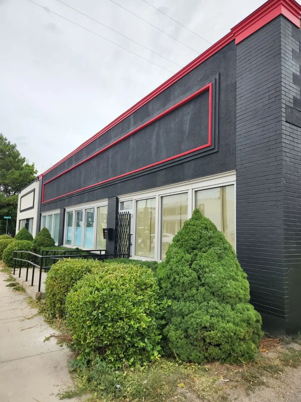 A dark brick commercial building with a red trimmed facade